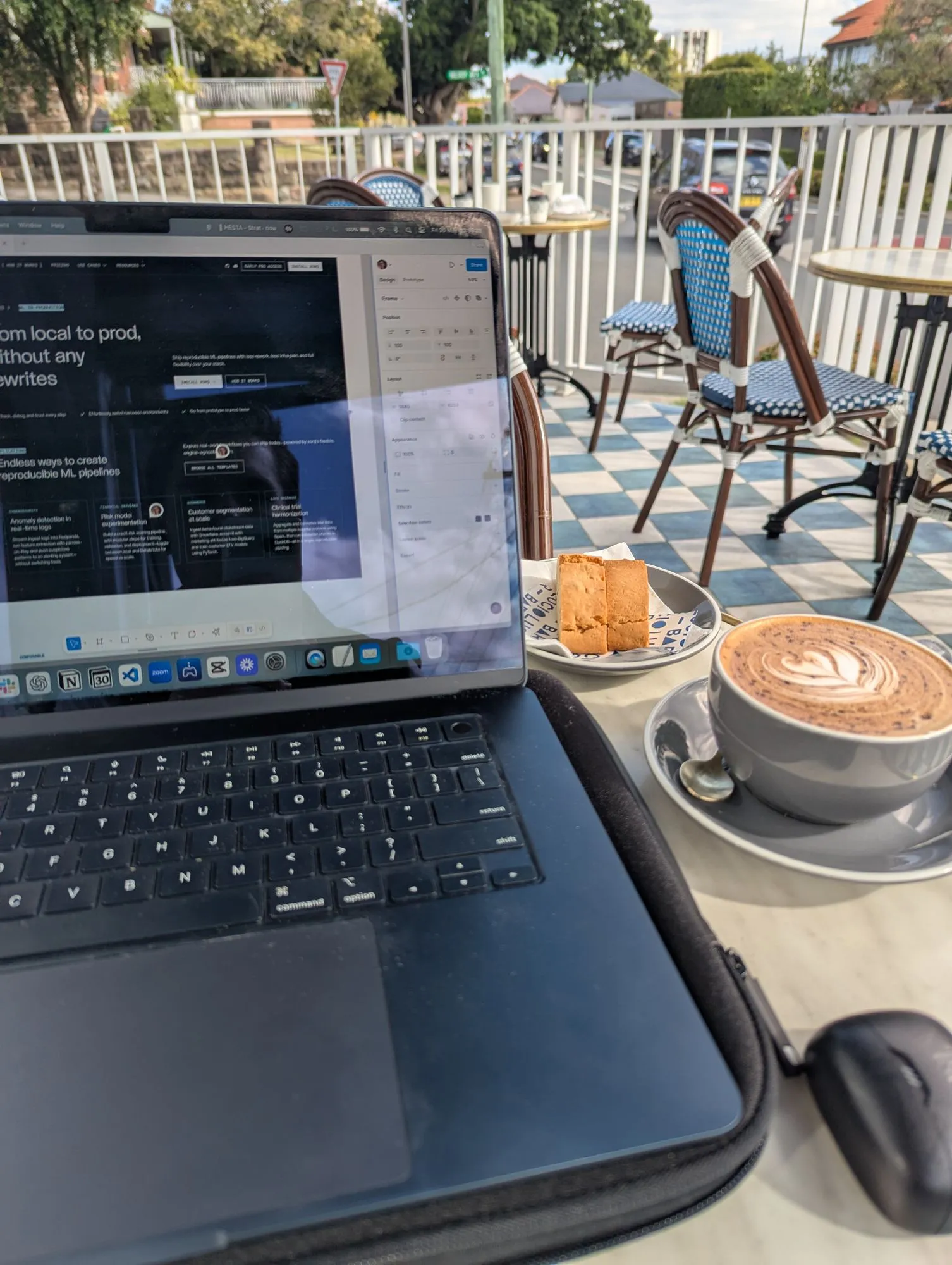 Laptop open on a design file beside a coffee at a cafe
